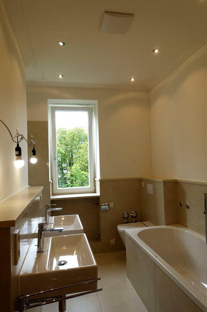 Badezimmer mit zwei Aufsatzbecken auf durchgehender Steinablage, Fenster und eingefasster Badewanne