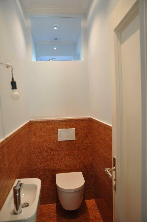 Gäste-WC mit rotbraun gefliesten Wänden und Boden, Wand-WC und kleinem Handwaschbecken